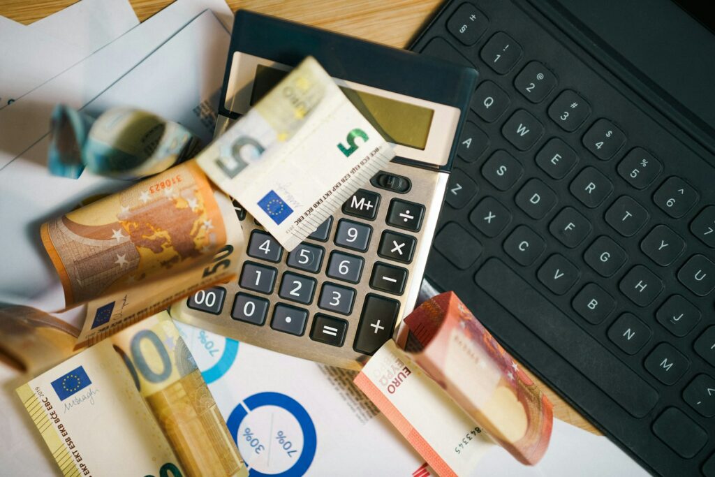 Billets en euros et calculatrice posés sur une table, image d’illustration pour un article sur le budget et les économies publiques.